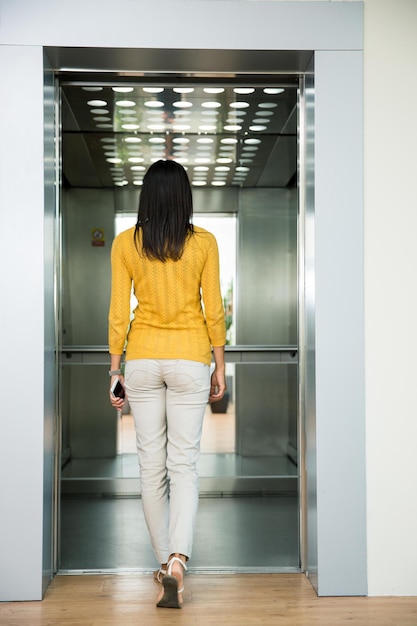 Back view portrait of a woman going in elevator indoors