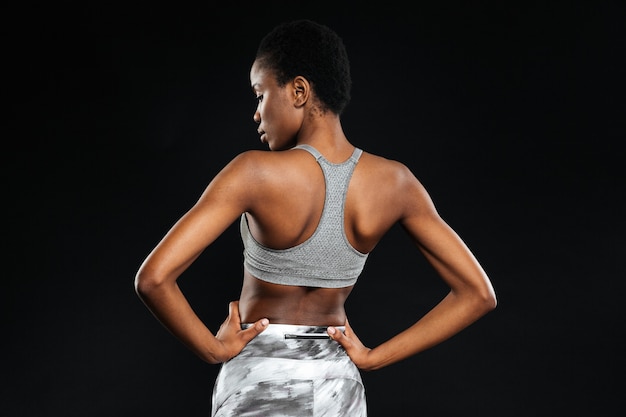 Back view portrait of a young woman stretching hands isolated on a white wall