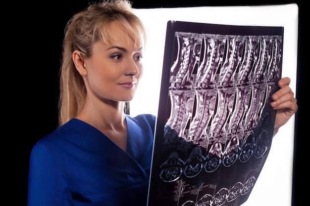 Back view of professional young doctor woman holding mri of cervical spine and looking at it