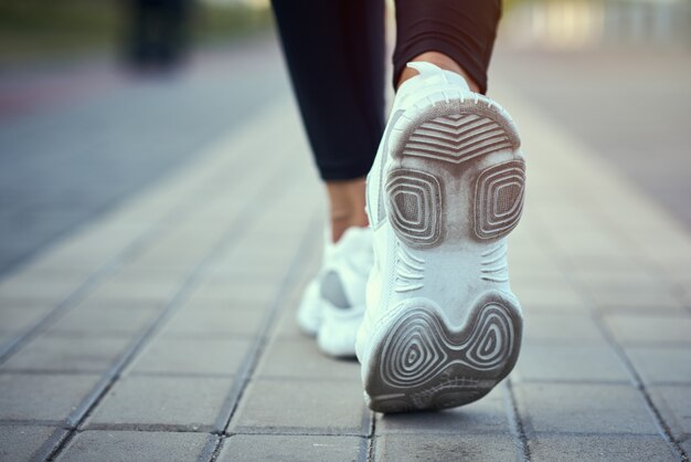 Back view of runner in sport sneakers running outdoors, clothe up