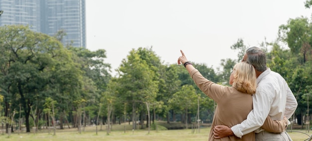 Photo back view of senior couple hand pointing forward talking together in the park