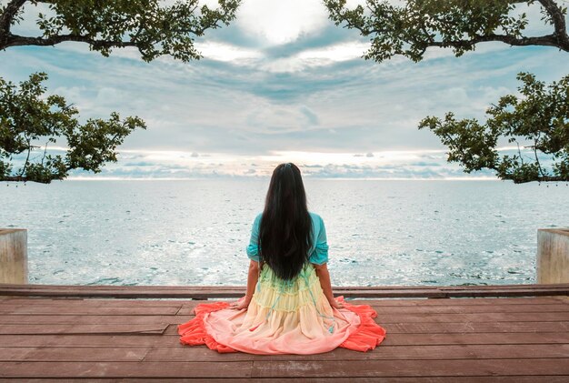 Back view single woman watching a sunset on the sea lifestyle or travel concept