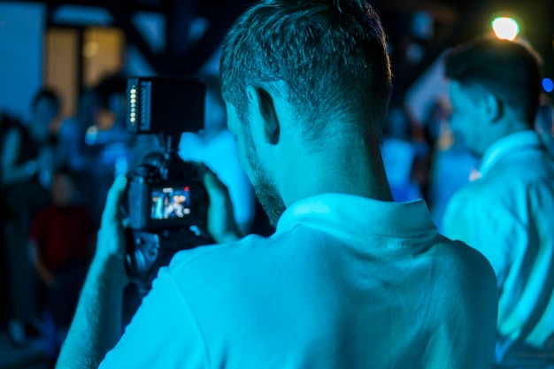 Back view of a single young man cameraman shooting the film\
scene with camera on street dslr camera