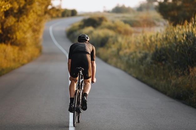 Back view of sportsman practicing in cycling on nature