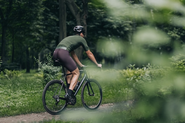 Вид сзади спортивного человека в спортивной одежде, езда на велосипеде на открытом воздухе