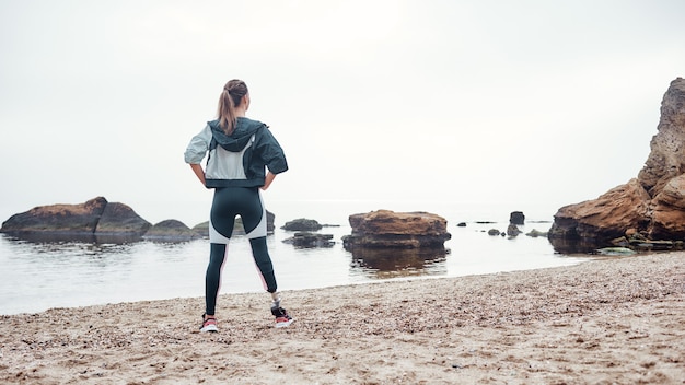 back view of strong and confident disabled woman in sportswear with prosthetic leg