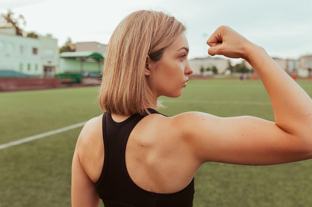 Back view of strong sportswoman showing muscular bicep