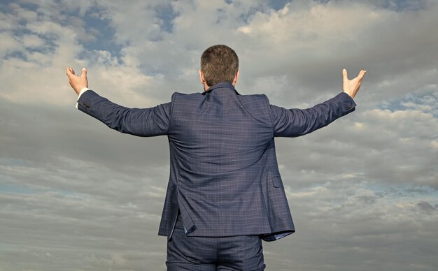スーツを着た成功したビジネスマンの後ろの景色 スーツの成功したビジネスマン 空の背景のスーツを着した成功したビジネスマーンの写真