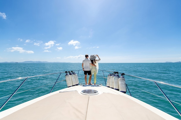 Back view of a sweet couple standing on edge of luxury yacht