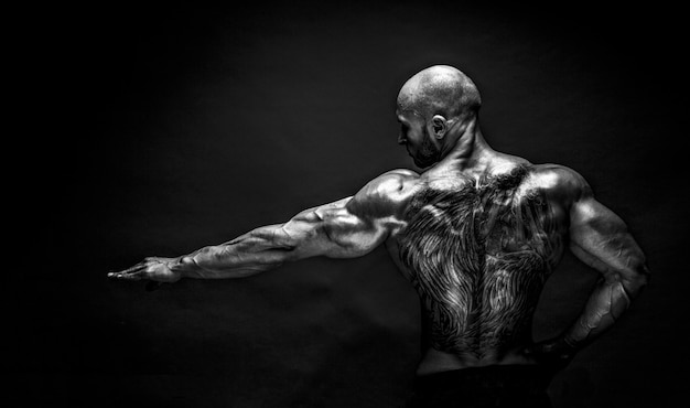 Back view of tattoed bodybuilder with outstretched arm