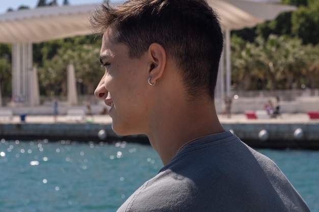 Back view teenager smiling in the port of Malaga looking at the sea.