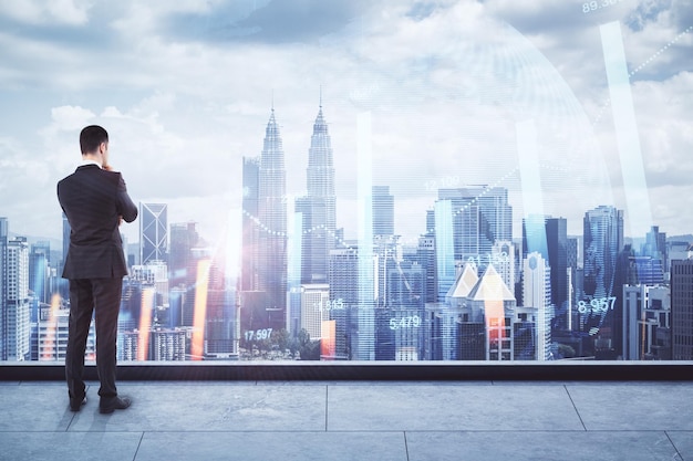 Back view of thoughtful young businessman looking at city view with forex chart Trade and market concept Double exposure