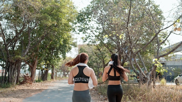 朝の健康的なライフスタイルの概念で一緒に屋外でジョギングする2人の女性ランナーの背面図