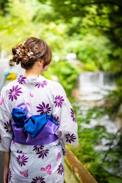 Back view of two women wearing Japanese yukata summer kimono walking on the road in nature