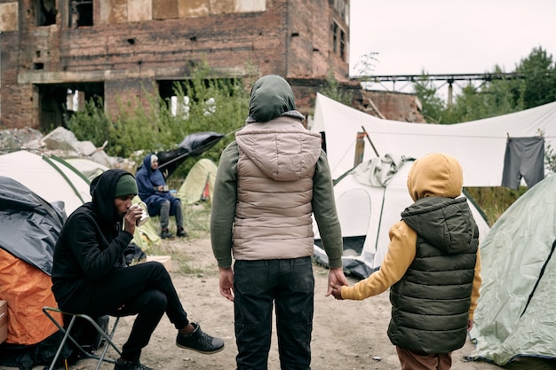 Photo back view of twow refugees standing in front of camp