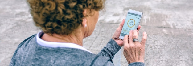 Вид сзади на неузнаваемую пожилую женщину, использующую смартфон у морского пирса