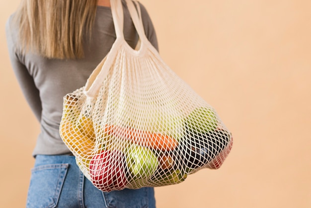 Foto vista posteriore donna che trasporta borsa riutilizzabile con generi alimentari