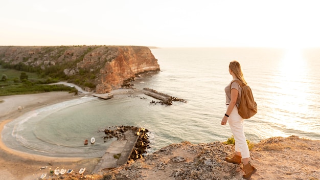 Back view woman enjoying the sunset on a coast with copy space