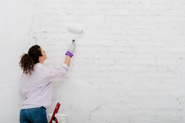 Back view woman painting wall