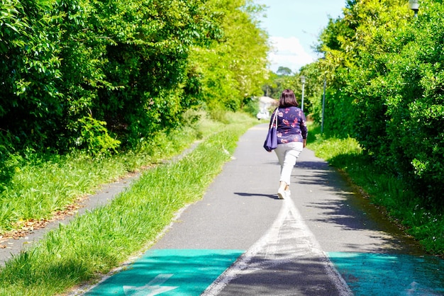 Photo back view of woman in pathway forest bike path walking in saint medard en jalles france