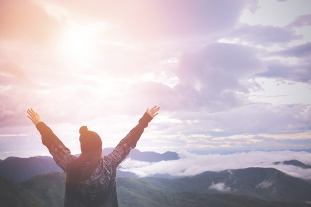 Back view of woman put hands up on landscape in morning.