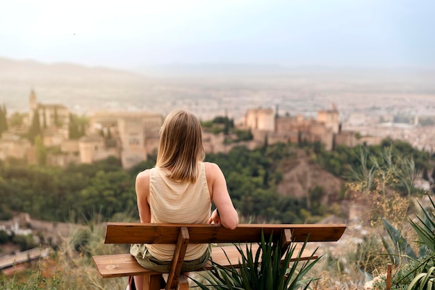 Back view of a woman seated in a viewpoint of granada
contemplating views visiting europe