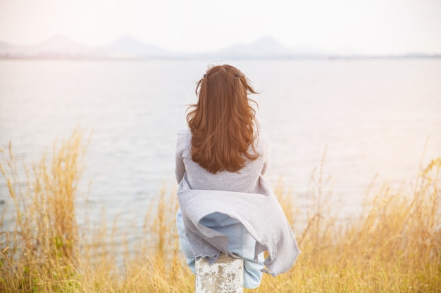 Back view of woman sit on the side of road with tree around, Asian traveler girl stand turn back and looking to far.