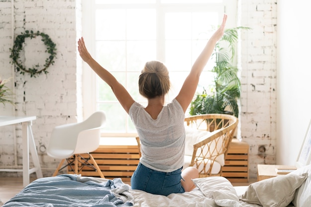 Foto donna di vista posteriore che allunga nella camera da letto