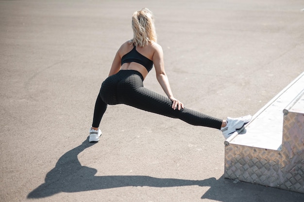 Back view of the woman stretching and warming up at urban stadium