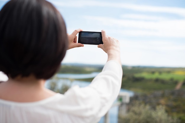 スマートフォンのカメラで写真を撮る女性の背面図