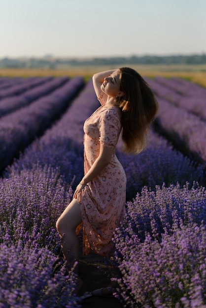 Photo back view of a woman walking along the rows of a lavender field