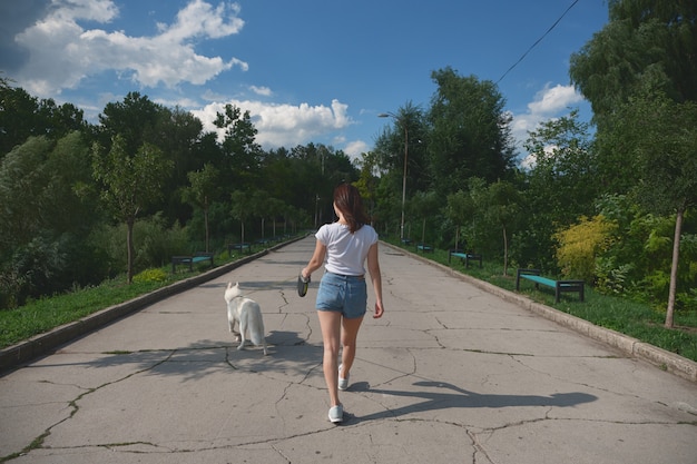 Back view woman walking her dog in the park