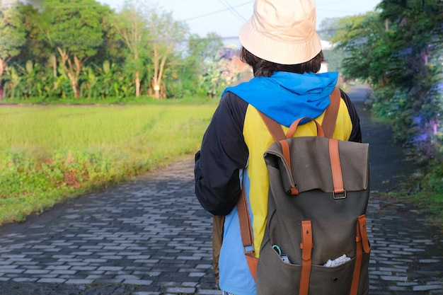 Back view A woman wearing a colorful jacket and a bucket hat is carrying a backpack