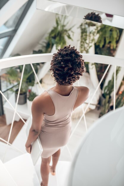 Back view of woman with laptop standing on stairs