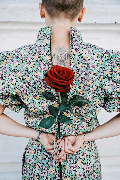 Back view of woman with tattoo Ukrainian trident symbol holds a red rose in her hands Ukrainian female volunteer patriotism Ukraine will win