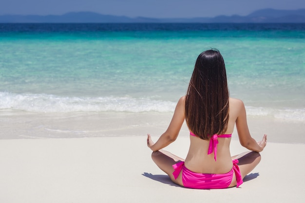 Back view of woman yoga on beach