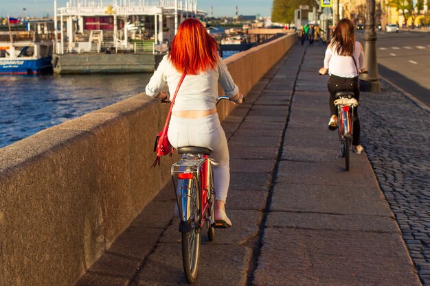 Back view of women riding bicycles in the afternoon along the embankment