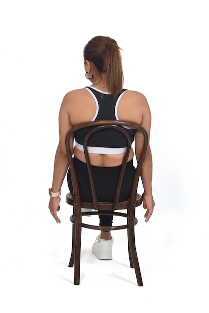 Back view of women sitting on chair with sportswear legs crossed on white background