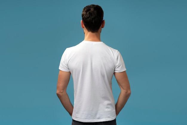 Back view of a young adult brunette businessman standing calmly over the blue background