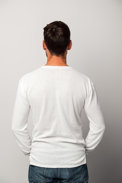 Back view of a young adult brunette businessman standing calmly over the while background Studio shot