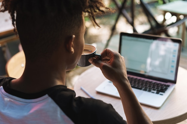 Back view of a young african man using laptop computer