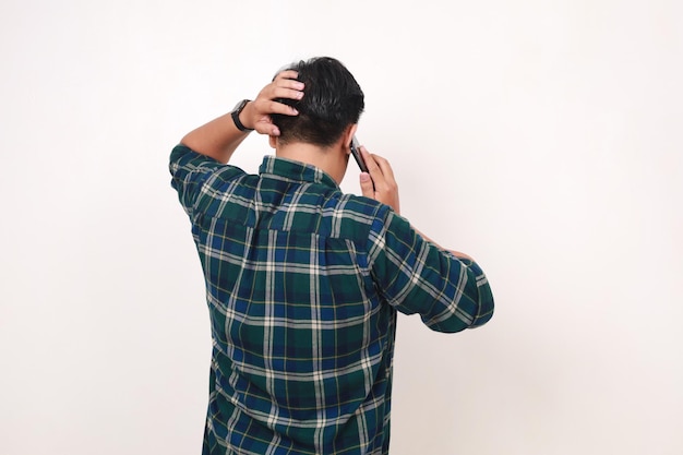 Back view of young asian man talking on the phone while holding his head