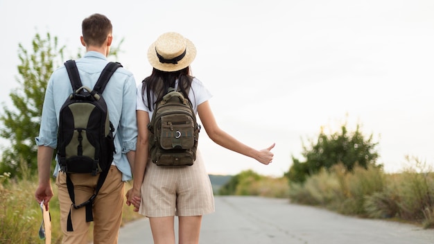 Photo back view young couple hitch hiking