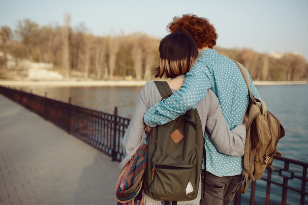 Photo back view young couple walking carefree in the park near the lake