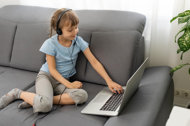 Back view of young girl sit at home, talk have online video call lesson with teacher or tutor, teenage schoolgirl engaged in webcam conversation, study distant use web conference app on laptop