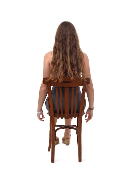 Back view of a young girl sitting on chair on white background