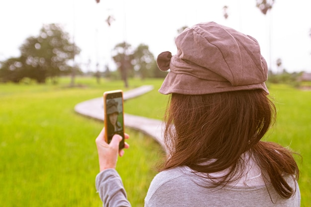 Back view of young girl taking selfie on mobile phone