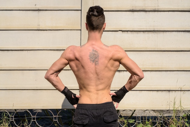 Vista posteriore di un uomo giovane combattente bello con corpo muscoloso magro all'aperto