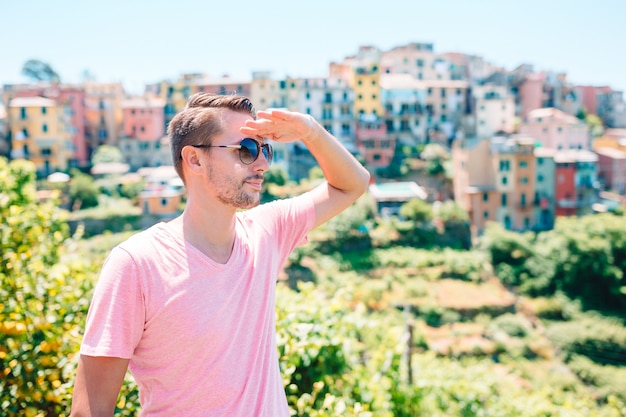 Back view of young man background stunning village. Tourist looking at scenic view of Manarola