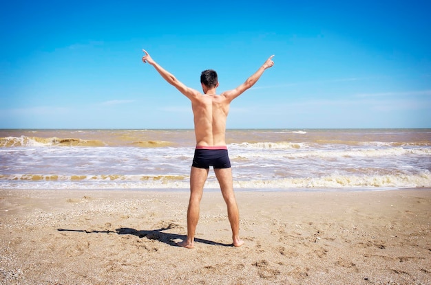 Back view of Young man spread his hands on beach